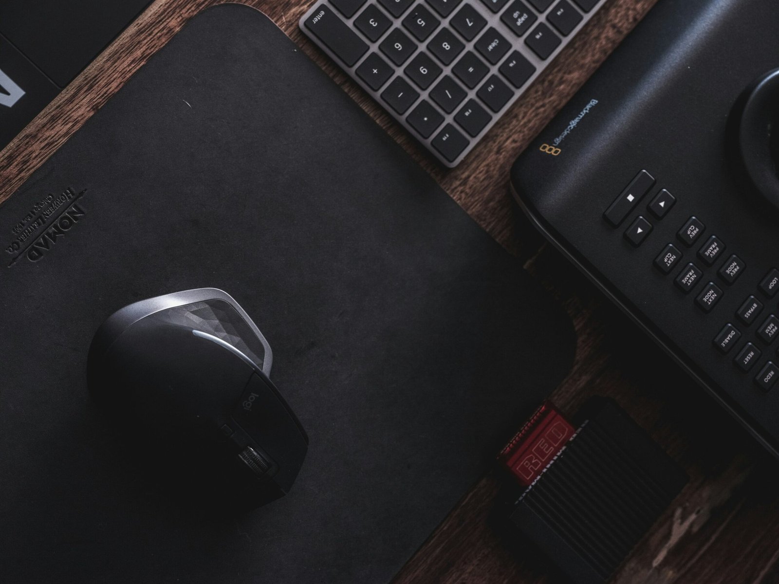Mouse e teclado sobre mousepad em uma mesa de trabalho.