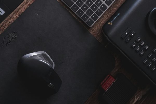 Mouse e teclado sobre mousepad em uma mesa de trabalho.